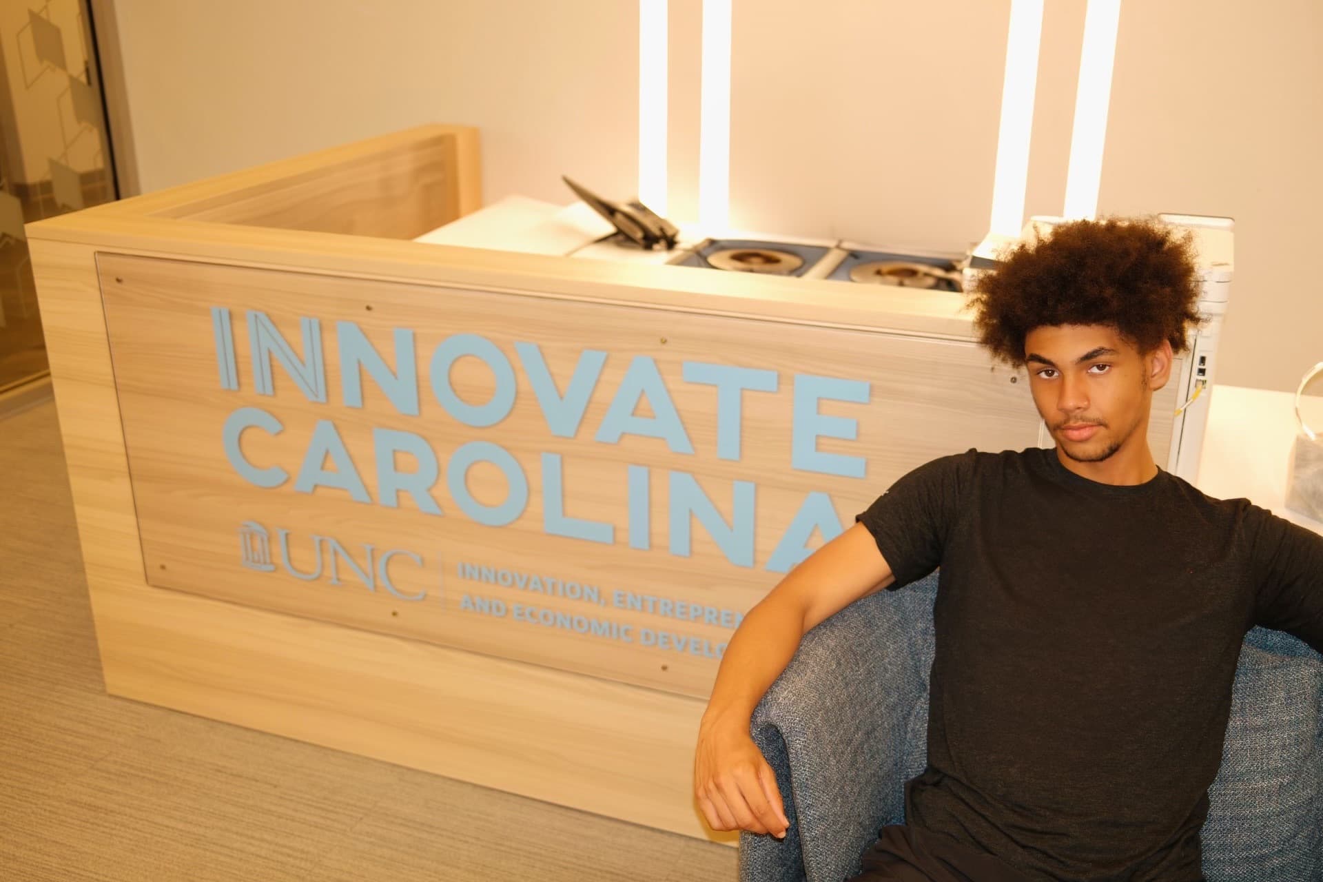 Joseph sitting in front of an Innovate Carolina sign